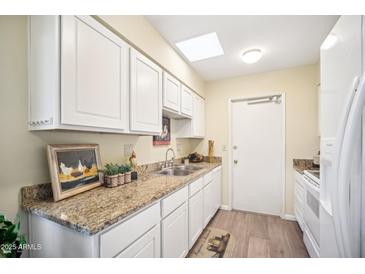 White cabinets, granite counters, and kitchen sink at 10606 W Granada Dr, Sun City, AZ 85373