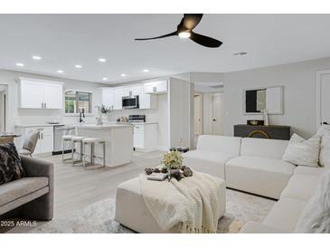 Open-concept living room featuring an island kitchen with white cabinets and modern appliances at 5232 E Dodge St, Mesa, AZ 85205