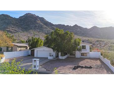 Single-story home with a white exterior, attached garage, and mountain views at 2343 E Orangewood Ave, Phoenix, AZ 85020