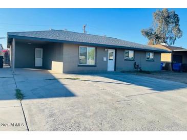 Ranch style home with gray exterior, large driveway, and mature trees at 4222 N 48Th Ave, Phoenix, AZ 85031