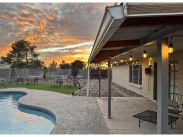 Beautiful backyard pool with artificial turf and a covered patio adorned with string lights at sunset at 5625 W Grovers Ave, Glendale, AZ 85308