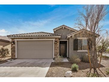 Charming single-story home with a two-car garage, stone accents, and desert landscaping at 26783 W Zachary Dr, Buckeye, AZ 85396