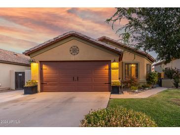 Well-maintained house with a brown garage door and landscaped front yard at 16209 W Davis Rd, Surprise, AZ 85374