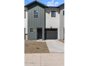 New construction gray townhome featuring a front door, garage and minimal landscaping at 7504 S 75Th Dr, Laveen, AZ 85339