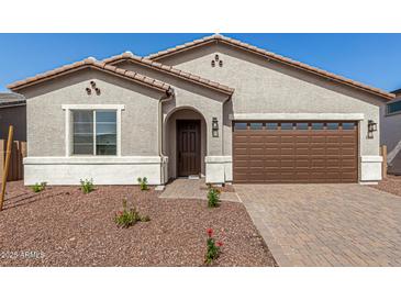 Charming single-story home featuring a well-manicured front yard, a brown garage door and a covered entry way at 17586 W Blue Sky Dr, Surprise, AZ 85387