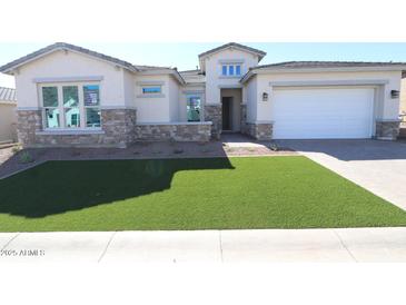 Charming single Gathering home featuring stone accents, a two-car garage, and freshly installed artificial turf at 21627 W Mariposa St, Buckeye, AZ 85396