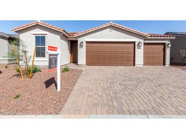 Inviting single-story home showcasing a two-car garage and terracotta roofing against a clear blue sky at 17868 W Blue Sky Dr, Surprise, AZ 85387