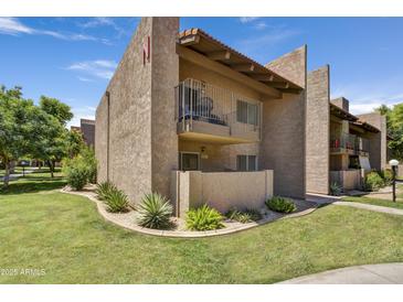 Exterior of a two-story stucco condo featuring a balcony, well-maintained landscaping, and lush green grass at 5525 E Thomas Rd # N1, Phoenix, AZ 85018