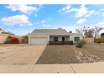 Single-story house with a gray exterior, modern wood accents, and a well-maintained front yard at 12130 N 70Th Ave, Peoria, AZ 85345