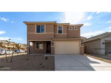 Two-story house with beige exterior, two-car garage, and landscaped front yard at 18337 W Poston Dr, Surprise, AZ 85387