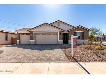 Charming single-story home featuring a brick driveway, a three-car garage, and desert landscaping at 12337 W Marguerite Ave, Avondale, AZ 85323