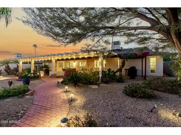 Landscaped backyard with covered patio, brick pathway, and lighting at 12715 W Beechwood Dr, Sun City West, AZ 85375