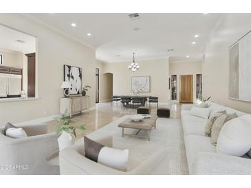 Open concept living and dining area with travertine floors, neutral decor, and a light wood front door at 8146 E Wingspan Way, Scottsdale, AZ 85255