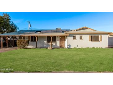 Charming single story home with green lawn, a fountain, and solar panels on the roof at 142 W Ivanhoe Pl, Chandler, AZ 85225
