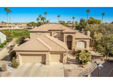 Luxury home with a tile roof, three-car garage, and a golf course view at 9048 E Cedar Waxwing Dr, Sun Lakes, AZ 85248