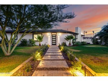Charming home exterior with walkway, manicured lawn, modern door, and warm landscape lighting at 1345 W Edgemont Ave, Phoenix, AZ 85007