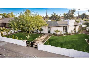 Charming home featuring a black privacy gate, manicured lawn and white painted brick perimeter at 1345 W Edgemont Ave, Phoenix, AZ 85007