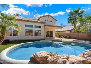Backyard featuring a sparkling pool, patio area and manicured lawn with lush palms; ideal for outdoor entertaining at 19406 N 31St Way, Phoenix, AZ 85050