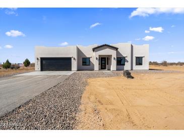 Stunning single-story home featuring a desert landscape and a black garage door on a sunny day at 30500 N 208Th Dr, Wittmann, AZ 85361