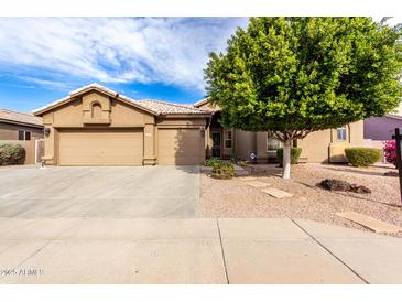 Tan two-story house with a three-car garage and nicely landscaped front yard at 9354 E Hillview Cir, Mesa, AZ 85207