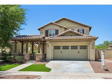 Charming two-story home with a desert landscape, a covered porch, and a two-car garage at 2542 N Riley Rd, Buckeye, AZ 85396