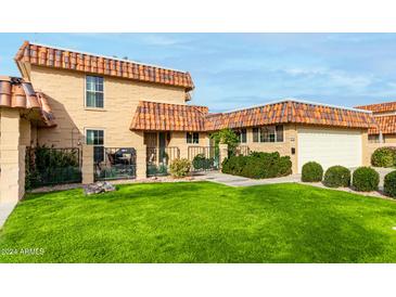 Tan two-story home with tile roof and landscaped yard at 9734 N 105Th Dr, Sun City, AZ 85351