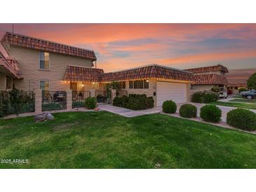 Charming home featuring a green lawn, unique tile roof, manicured bushes and an attached two-car garage at 9734 N 105Th Dr, Sun City, AZ 85351