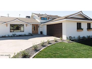 White two-story home with brown garage door and landscaped lawn at 8437 E San Miguel Ave, Scottsdale, AZ 85250