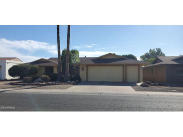 Tan house with a two-car garage and nicely landscaped yard at 13359 W Ballad Dr, Sun City West, AZ 85375