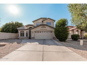 Two-story house with tan exterior, attached garage, and landscaping at 553 E Kyle Ct, Gilbert, AZ 85296