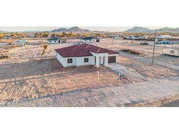 New construction shows a tan house with a red tile roof against the backdrop of distant mountains and open desert at 21165 W Carver Rd, Buckeye, AZ 85326