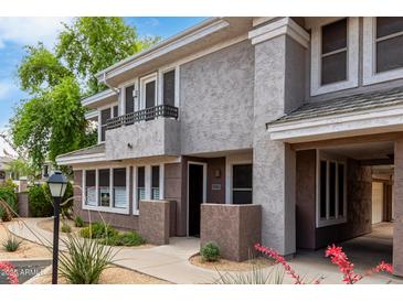Inviting two-story condo featuring a stucco exterior, charming balcony, and well-maintained landscaping at 15221 N Clubgate Dr # 1110, Scottsdale, AZ 85254
