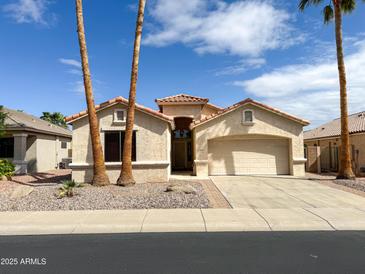 Charming single-story home with a terra cotta tile roof, palm trees, and low maintenance desert landscaping at 18068 W Browning Dr, Surprise, AZ 85374