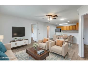 Open living room features hardwood floors, and a view into the kitchen and dining area at 14300 W Bell Rd # 65, Surprise, AZ 85374