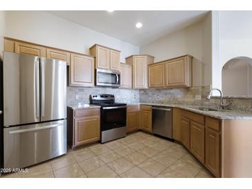 Bright kitchen features stainless steel appliances, tile backsplash, and granite countertops at 14575 W Mountain View Blvd # 11317, Surprise, AZ 85374