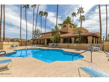 Community pool with surrounding lounge chairs and patio tables at 8344 N 21St Dr # I105, Phoenix, AZ 85021