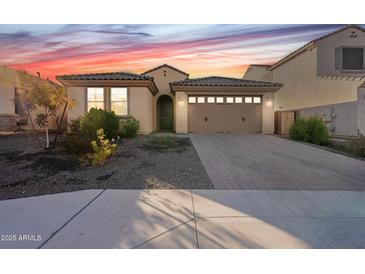 Charming single-story home with a tile roof and a two-car garage at dusk at 6807 W Winston Dr, Laveen, AZ 85339