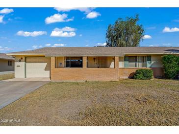 Brick ranch house with carport, covered porch, and a well-maintained lawn at 10632 W Roundelay Cir, Sun City, AZ 85351