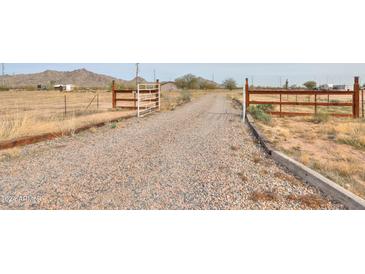 Gravel driveway leading to a ranch style home with wooden gates at 11865 N Allegro Rd, Maricopa, AZ 85139