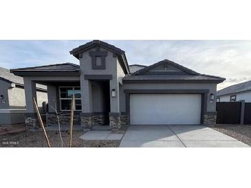 New single-story home with gray exterior, stone accents, and a two-car garage at 25431 W Graham Trl, Buckeye, AZ 85326