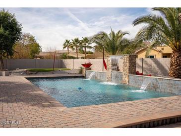 Refreshing swimming pool with a waterfall feature and a spacious patio area at 3410 N 131St Ln, Litchfield Park, AZ 85340