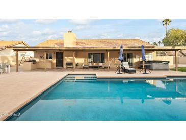 Inviting backyard oasis featuring a sparkling pool, covered patio, and built-in BBQ at 13454 N 88Th Pl, Scottsdale, AZ 85260