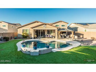 Inviting backyard oasis with sparkling pool, covered patio, and lush landscaping at 44049 W Palo Nuez St, Maricopa, AZ 85138