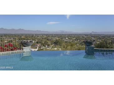 Stunning infinity pool overlooks a panoramic mountain and city vista at 7150 N 64Th Pl, Paradise Valley, AZ 85253