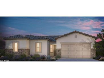 Single-story home with tan exterior, brick accents, and a 2-car garage at 18144 W Tanglewood Dr, Goodyear, AZ 85338