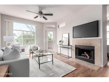 Bright living room boasts a fireplace, ceiling fan, view to the outside, and comfortable seating arrangements at 3830 E Lakewood E Pkwy # 2154, Phoenix, AZ 85048