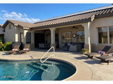 Inviting backyard oasis with a sparkling pool, spacious patio, and comfortable lounge area at 12803 W Campina Dr, Litchfield Park, AZ 85340