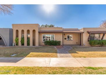 Tan two-story home with arched entryways and landscaped lawn at 1833 W Citrus Way, Phoenix, AZ 85015