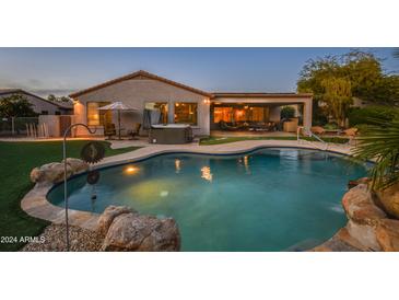 Inviting backyard oasis with a sparkling pool, spa, and covered patio at 21705 N Black Bear Lodge Dr, Surprise, AZ 85387