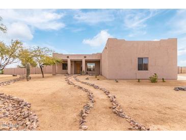 Desert landscape with stucco home, stone pathway, and mature trees at 22605 W Baker Dr, Wittmann, AZ 85361